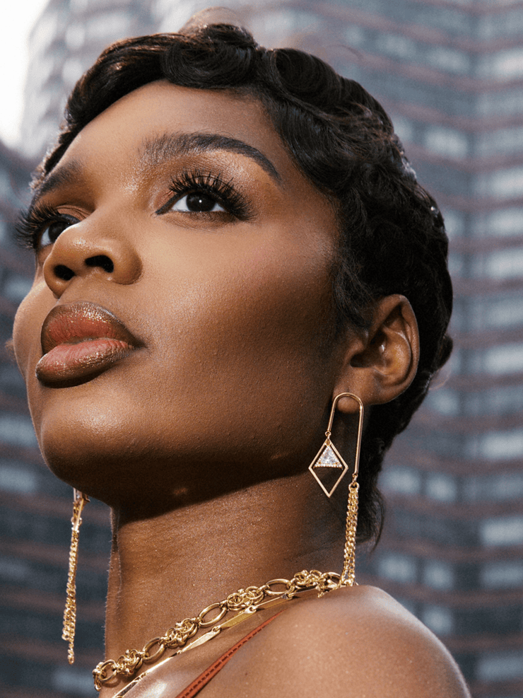 DIPHDA Cosmic Waterfall Earrings with cubic zirconia triangle charms and gold chain fringe, displayed against a celestial backdrop