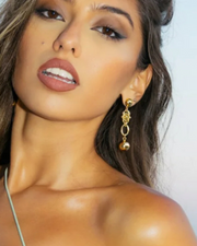 DIPHDA Eclipse Earrings in Gold on gorgeous model - Half ball stud with a handmade unique interwoven large chain with a hollow golden ball hanging from end- looks expensive yet edgy, classic yet modern.