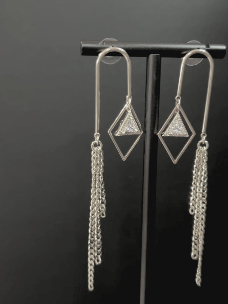 DIPHDA Cosmic Waterfall Earrings with cubic zirconia triangle charms and gold chain fringe, displayed against a celestial backdrop